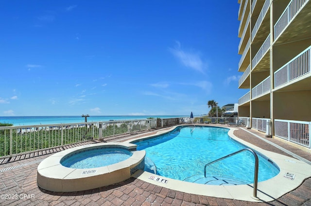 view of swimming pool with a patio area, a hot tub, and a water view