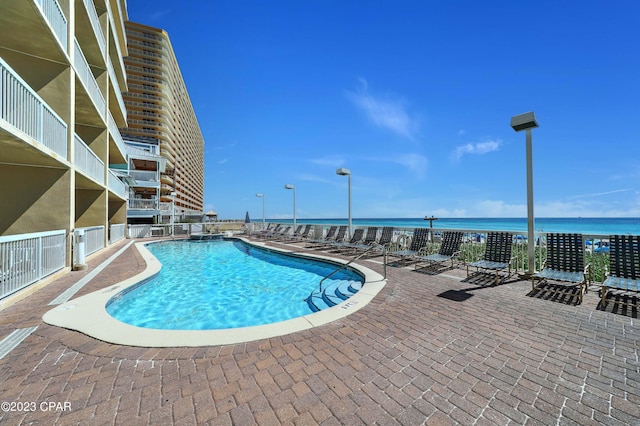 view of pool with a water view and a patio