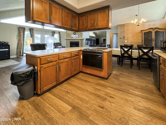 kitchen with kitchen peninsula, light wood-type flooring, hanging light fixtures, and a notable chandelier