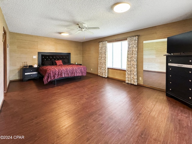 bedroom with ceiling fan, dark hardwood / wood-style flooring, and a textured ceiling