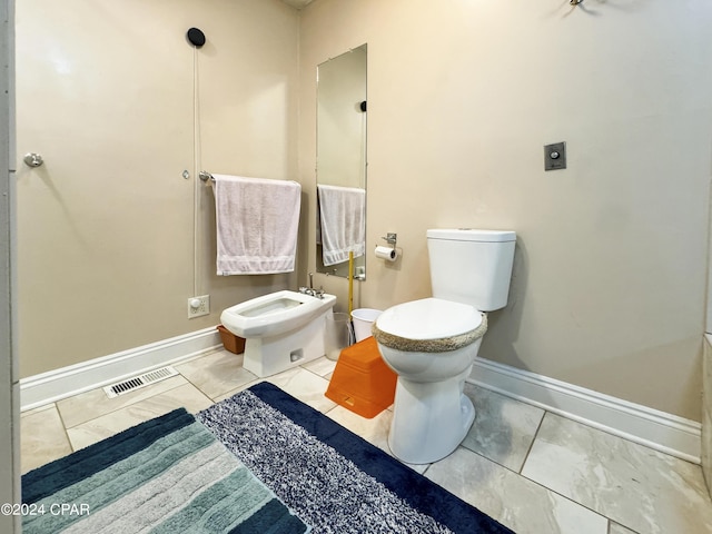 bathroom featuring tile patterned flooring, toilet, and a bidet