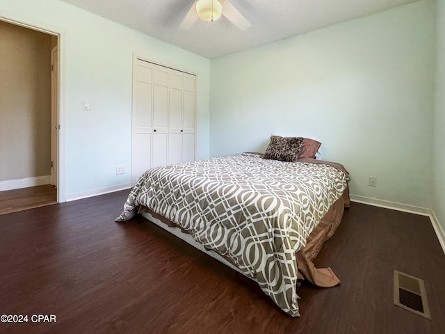 bedroom with dark hardwood / wood-style flooring, a textured ceiling, a closet, and ceiling fan