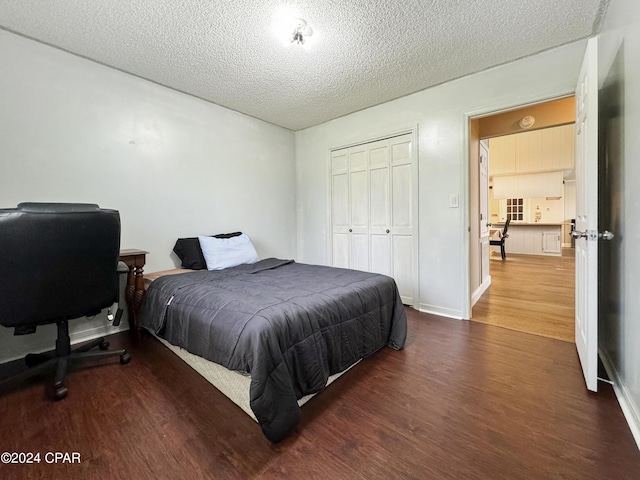 bedroom with a textured ceiling, dark hardwood / wood-style floors, and a closet