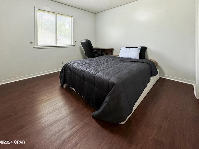 bedroom featuring a textured ceiling and dark hardwood / wood-style floors