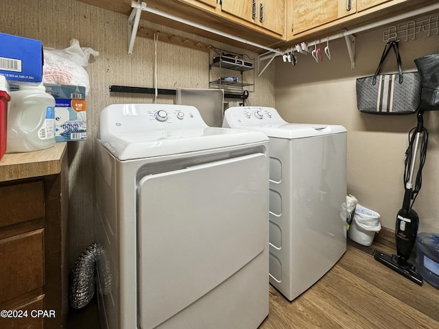 clothes washing area with cabinets, light wood-type flooring, and washing machine and clothes dryer