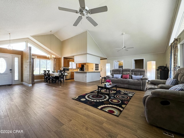 living room featuring a textured ceiling, high vaulted ceiling, dark wood-type flooring, and ceiling fan with notable chandelier