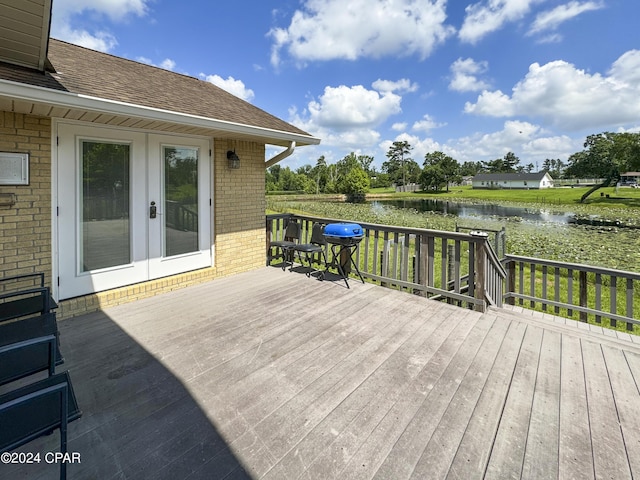 deck featuring a water view, a grill, and french doors