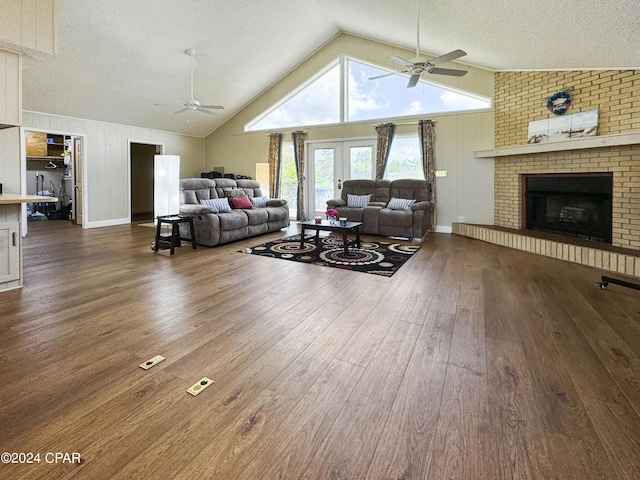 living room featuring french doors, a brick fireplace, a textured ceiling, dark wood-type flooring, and lofted ceiling