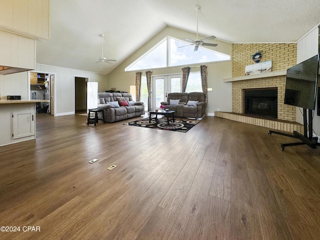 living room featuring french doors, dark hardwood / wood-style flooring, ceiling fan, high vaulted ceiling, and a fireplace