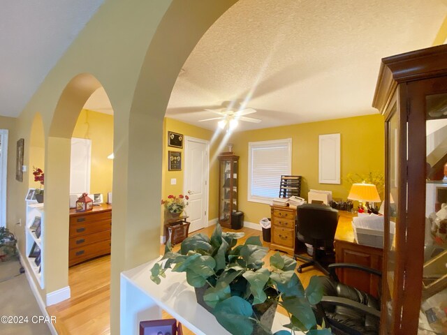 home office with light wood-type flooring, a textured ceiling, and ceiling fan