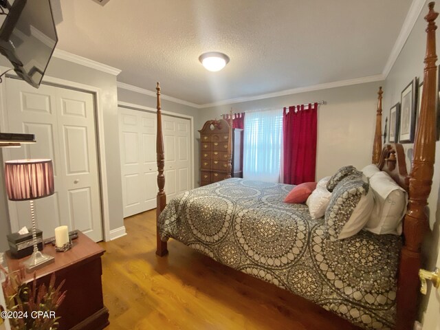 bedroom with wood-type flooring, a textured ceiling, and crown molding