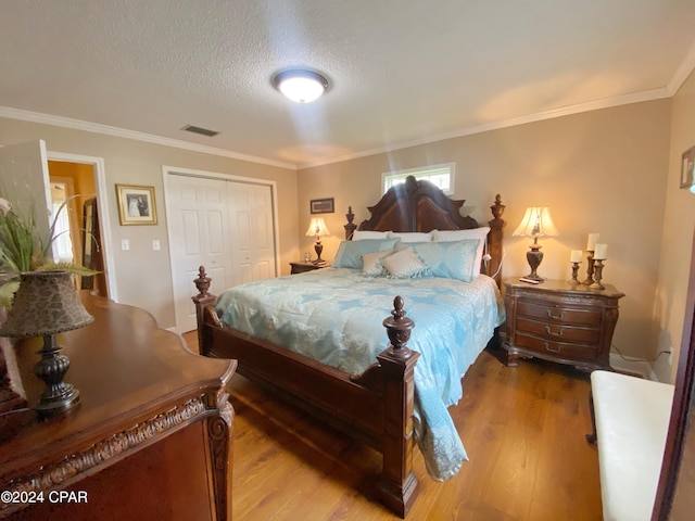 bedroom with crown molding, hardwood / wood-style flooring, a closet, and a textured ceiling