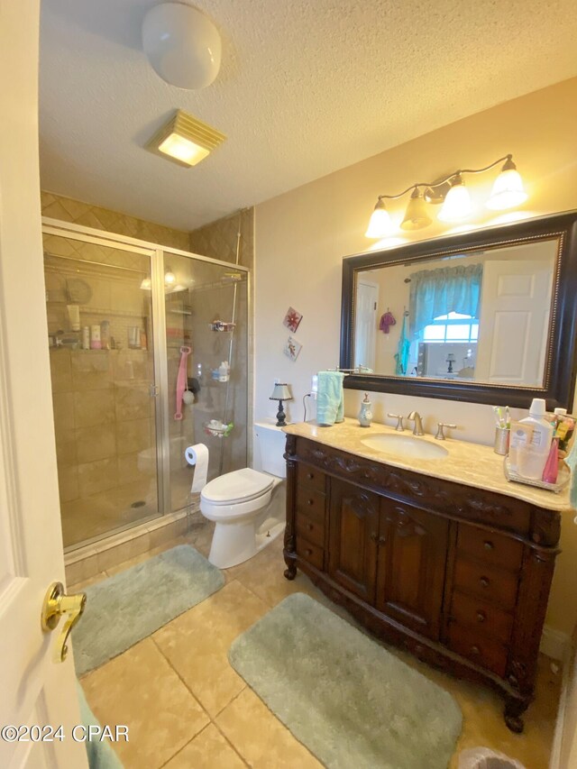 bathroom featuring tile flooring, walk in shower, a textured ceiling, toilet, and vanity