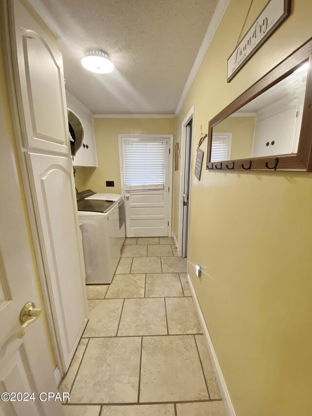 laundry area with independent washer and dryer, a textured ceiling, light tile floors, ornamental molding, and cabinets