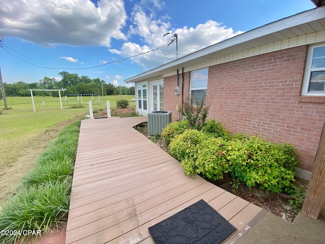 wooden deck with a yard and central AC unit