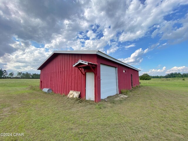 view of outdoor structure with a rural view, a garage, and a yard