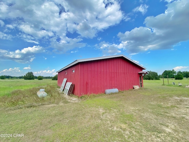 view of outdoor structure featuring a rural view and a lawn