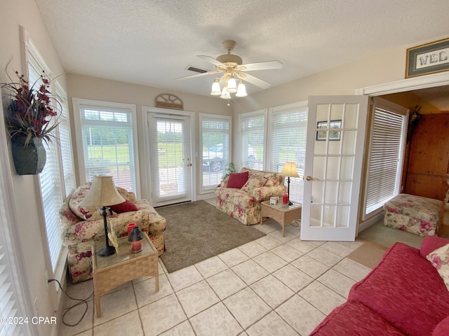 tiled living room featuring a textured ceiling, ceiling fan, and french doors