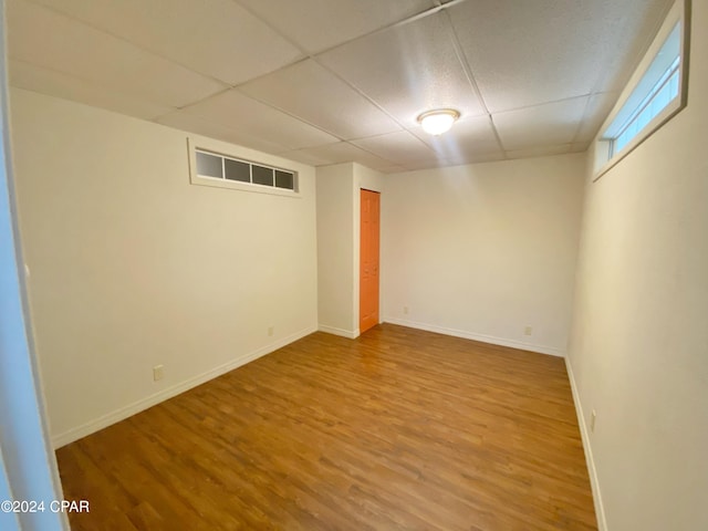 basement with hardwood / wood-style floors and a paneled ceiling