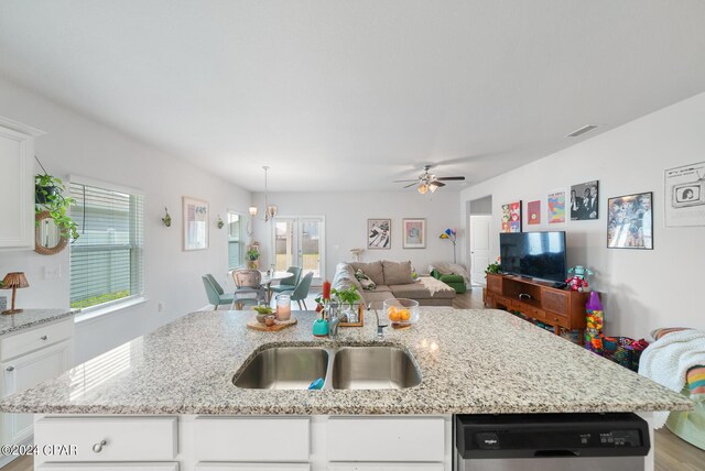 kitchen featuring stainless steel dishwasher, white cabinetry, wood-type flooring, and a center island with sink