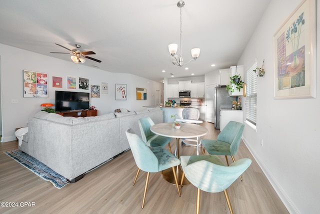 dining room featuring ceiling fan with notable chandelier and light hardwood / wood-style flooring