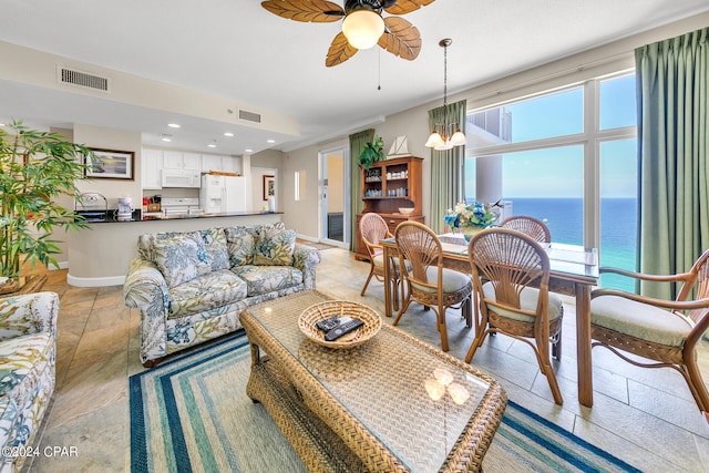 living room with ceiling fan with notable chandelier, a water view, and plenty of natural light