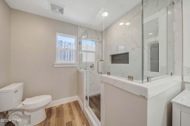 bathroom featuring hardwood / wood-style floors, vanity, toilet, and a shower with door