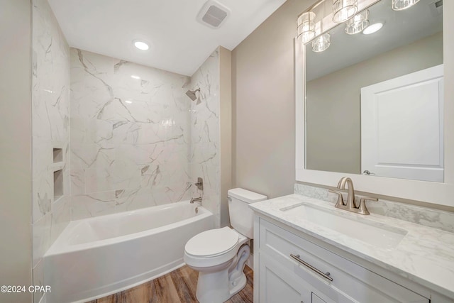 full bathroom with tiled shower / bath, vanity, toilet, and hardwood / wood-style floors