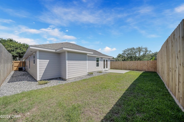 rear view of property with a lawn, a patio area, and central air condition unit