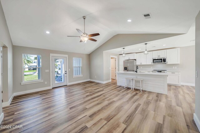 kitchen featuring white cabinetry, sink, hanging light fixtures, light hardwood / wood-style flooring, and appliances with stainless steel finishes