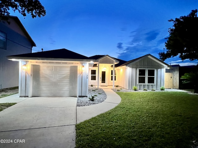 ranch-style house with a garage and a lawn