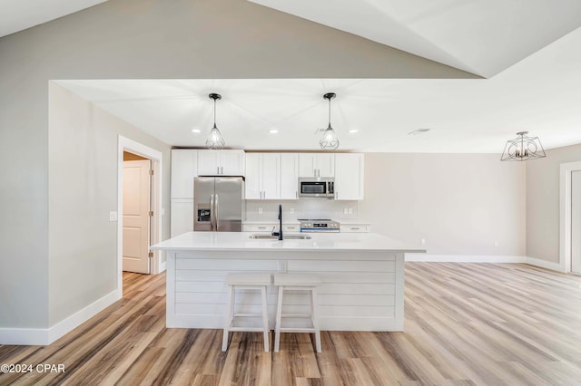 kitchen with decorative light fixtures, an island with sink, lofted ceiling, white cabinetry, and stainless steel appliances