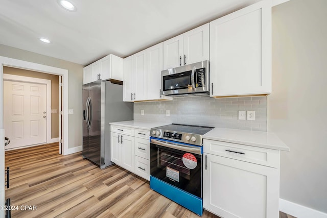 kitchen with decorative backsplash, stainless steel appliances, white cabinetry, and light hardwood / wood-style flooring