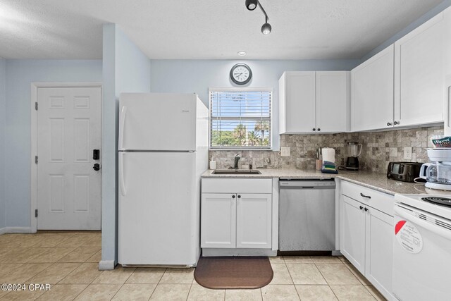 kitchen with sink, white cabinets, white appliances, and light tile patterned floors