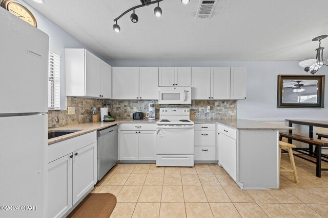 kitchen featuring white appliances, decorative light fixtures, white cabinetry, and backsplash