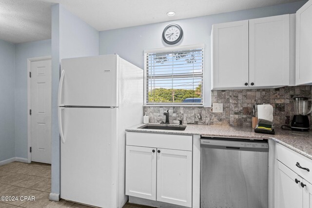 kitchen featuring sink, stainless steel dishwasher, white refrigerator, decorative backsplash, and white cabinets