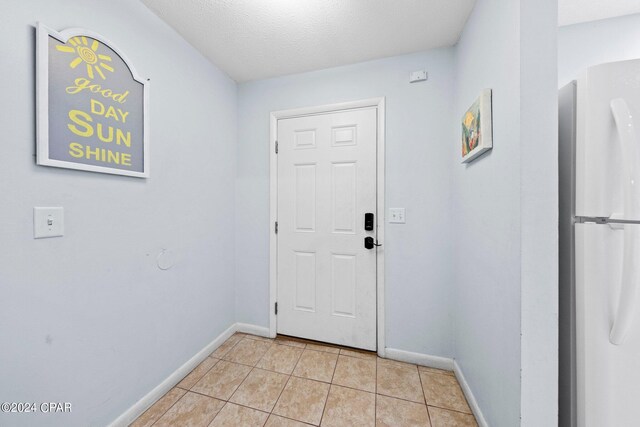 doorway to outside featuring light tile patterned floors and a textured ceiling