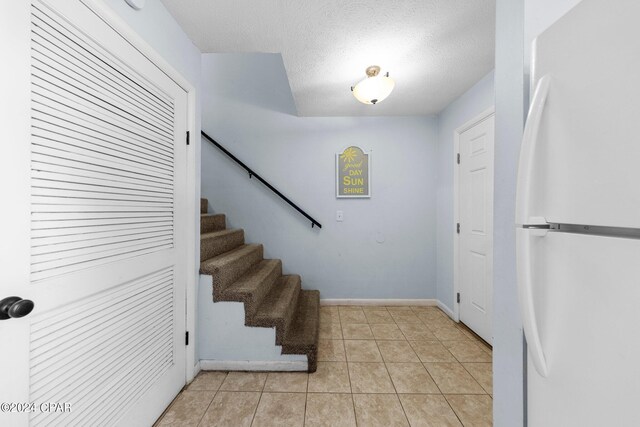 foyer with light tile patterned flooring and a textured ceiling