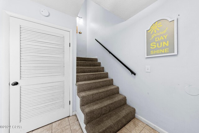 staircase featuring tile patterned floors and a textured ceiling