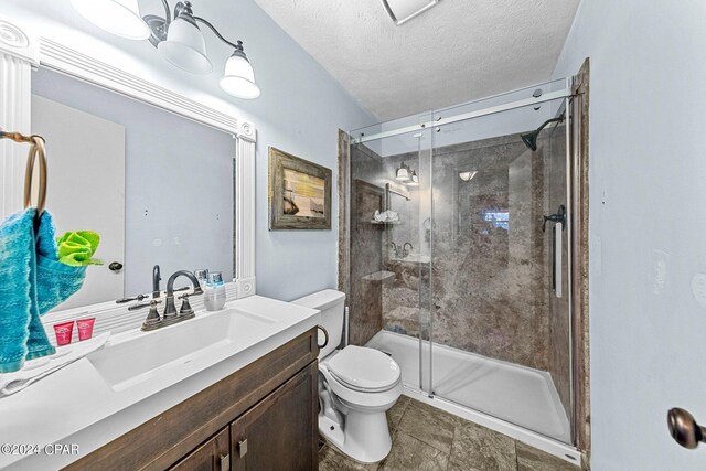 bathroom featuring an enclosed shower, vanity, toilet, and a textured ceiling