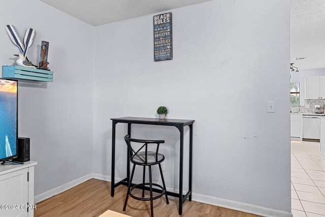 interior details with dishwashing machine, wood-type flooring, a textured ceiling, and decorative backsplash