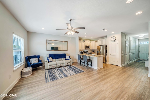 living room with light hardwood / wood-style flooring and ceiling fan