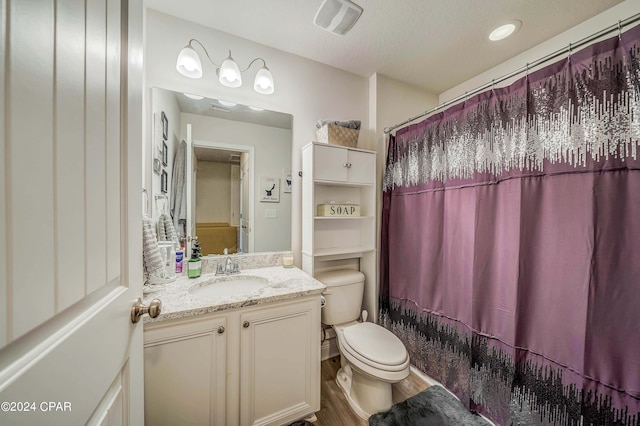 full bathroom featuring vanity, hardwood / wood-style flooring, toilet, shower / bath combo with shower curtain, and a textured ceiling