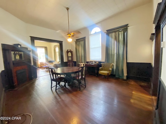 dining room with dark hardwood / wood-style flooring, ceiling fan, and a fireplace