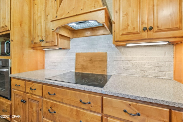 kitchen featuring stainless steel appliances, custom exhaust hood, and brick wall