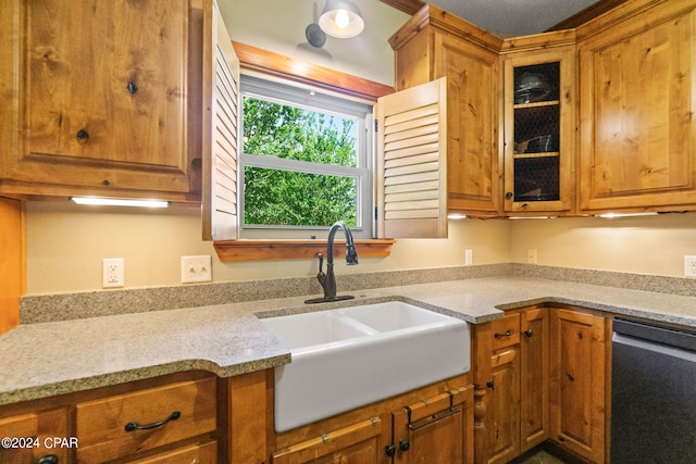 kitchen with dishwasher, sink, and light stone counters