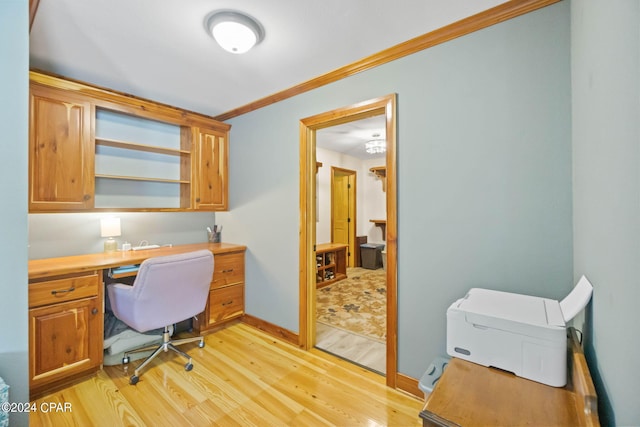 home office featuring built in desk, light hardwood / wood-style flooring, and crown molding