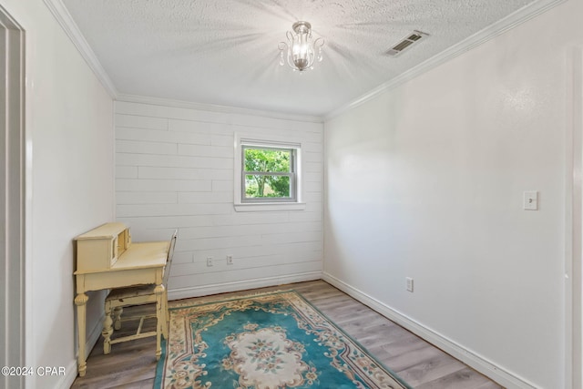 interior space with ornamental molding, a textured ceiling, and wood-type flooring