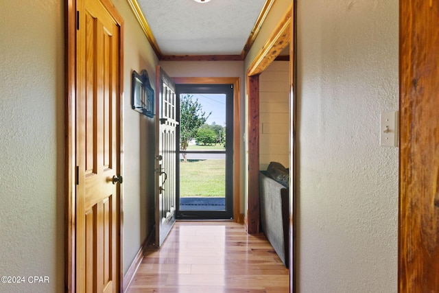 doorway to outside with crown molding, a textured ceiling, and hardwood / wood-style floors