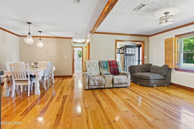 living room with a chandelier, a textured ceiling, and light hardwood / wood-style flooring